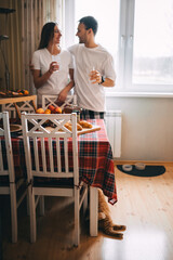 Couple enjoying drinks by the table in a cozy dining room during a relaxed morning