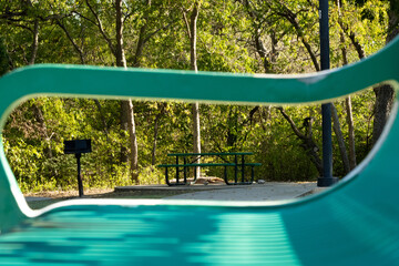 Park bench with scenic park setting in trees and sunlight. 