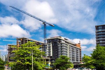 Construction of high-rise buildings in Richmond City, industrial construction site, construction equipment, several construction cranes  on the background of a blue cloudy sky