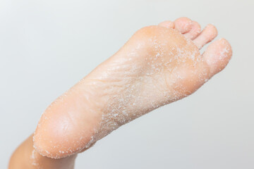 A close-up photo of a woman's foot with a sugar scrub applied to the skin. Beauty and hygiene. Pedicure and foot care.