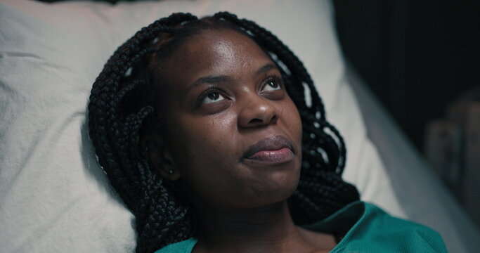 African woman patient, deep in thought, her gaze fixed above.