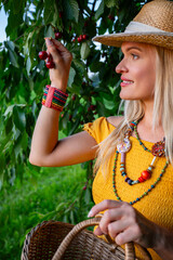 Smiling Female Farmer Holding Ripe Red Cherries Beneath a Cherry Tree on a Warm Spring Day
