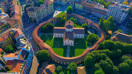 Aerial view of the Rotunda della Besana. Blue sky. Historical buildings in the city. A cruciform church surrounded by a wall. Cinematic drone. Tiled roofs. architecture Milan Italy 22.04.2025