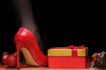 woman's leg in red stiletto heel next to gift in box