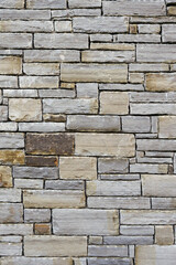 A wall made of gray bricks. The wall is very old and has a lot of cracks. Texture background for design. Stone mason craft.