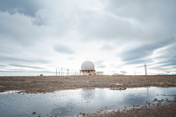 A radar station sits atop the rocky cliffs of Bolafjall mountain in Iceland's Westfjords, near...