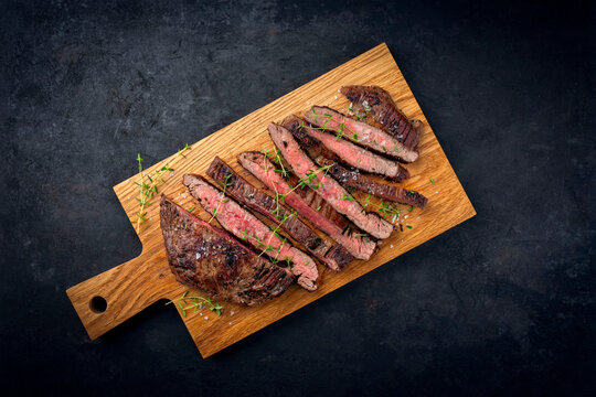 Barbecue grilled dry aged meat wagyu beef flank steak cut as tagliata on wooden board with text space