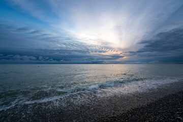 An incoming wave on the Black Sea and a pebble beach on the Sochi coast on a summer day with...