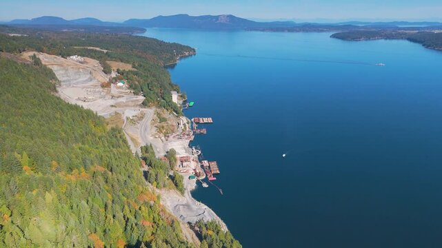 Aerial view of a quarry on the Saanich Peninsula shoreline, with lush green trees and a clear blue body of water in Victoria BC Canada