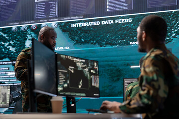 Cybersecurity team operates in an advanced military command center, managing surveillance systems...