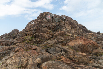 View of dark sea rocks against the ocean and cloudy sky. Preserved nature.