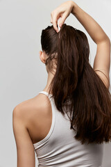 Fototapeta premium Woman styling her long hair with a sleek appearance on a plain light background, illustrating beauty and self care Hair care and personal grooming concepts showcased effectively