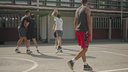 Teenage boys playing basketball on a sunny day in the schoolyard. Friends enjoying their free time together. Active lifestyle, sport, and friendship.