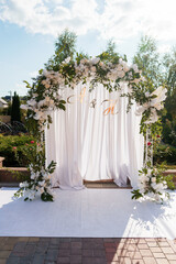 Elegant Floral Wedding Arch with White Drapery and Golden Initials