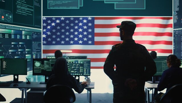 American military personnel ensuring servers protection and classified information, protecting state secrets in high tech agency office. Army soldier supervises hacking activity. Camera B.