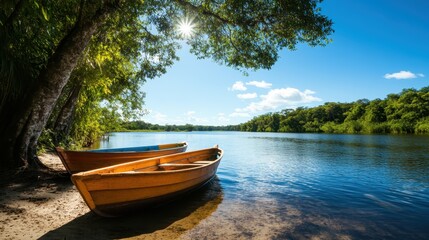 Wooden boats rest gently on a peaceful lakeside, shaded by lush green trees, all beneath a clear blue sky illuminated by the bright, warm sun.