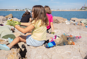 Young volunteers cleaning coastal area of marine debris