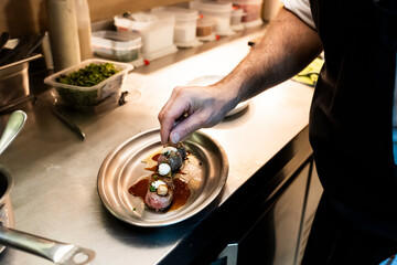 Professional chef carefully plating gourmet dish