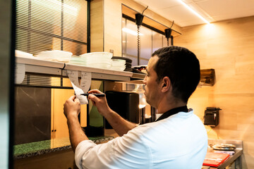 Chef reviewing orders in a busy restaurant kitchen
