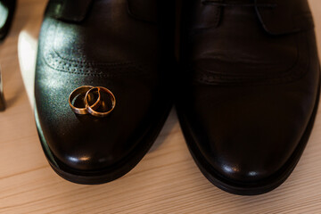 Elegant Wedding Rings Resting on Polished Black Leather Shoes