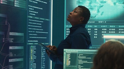 Professional IT expert working in a governmental security operations center, analyzing data on a big screen. Highlighting the importance of cyber security monitoring and threat analysis. Camera A.