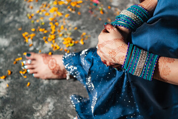 A traditional Indian woman is dressed in a saree, adorned with beautiful bangles and henna designs...