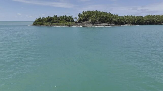 Drone flies over the beautiful blue Atlantic Ocean, then over Alfred Dreyfus Prison on a palm-tree infested Devil's Island in the Salvation Islands, near Kourou, French Guiana, France