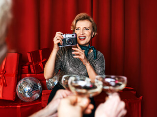 Cheerful beautiful photographer woman at the party celebration on red curtains background....