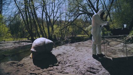The scientist in a chemical protective suit standing next to a giant snail.