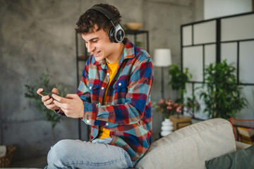 Adult young man with headphones play video games on mobile phone