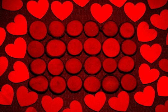 Wooden buttons surrounded by wood love hearts, with the image bathed in red light.