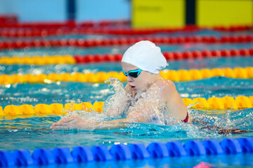 Swimmer child swims breaststroke swimming style in the pool