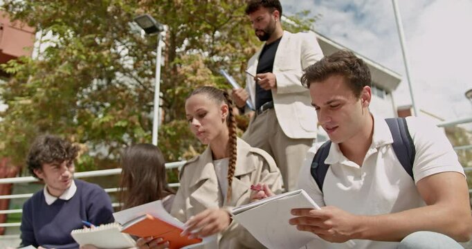 Students solve individual tasks in an outdoor class as professor watches and helps. Back to school. Education.