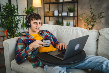 Relax adult man with headphones watch movie on laptop and drink coffee