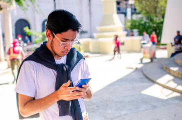 Medium shot of a young Latino man texting on his smartphone. High angle shot.