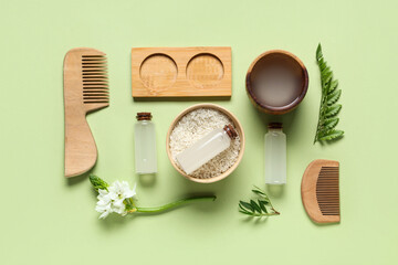 Composition with rice water, grains, wooden hair combs and plants on green background