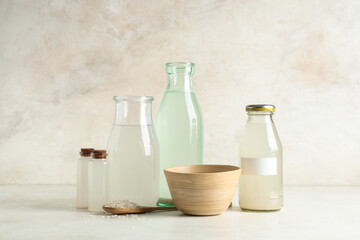 Different bottles of rice water and grains on light background