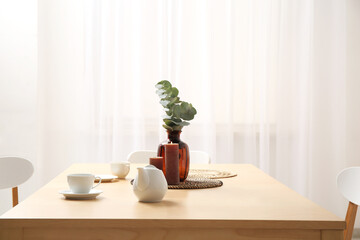 Table with teapot and cups in interior of dining room