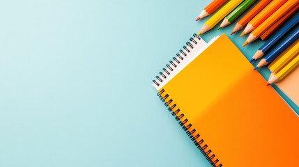 A collection of vibrantly colored pencils arranged beside a spiral notebook, showcasing creativity and organization against a pastel blue background. Ideal for art lovers.