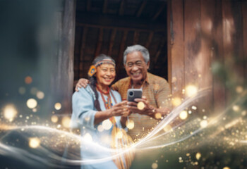 Obraz premium An elderly couple, dressed in traditional clothing, smiles while looking at a smartphone. The background features a wooden door and shimmering lights.