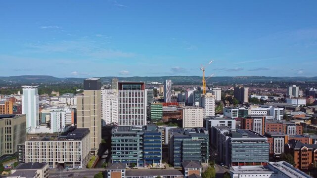 Aerial drone footage of Cardiff city centre as seen from Atlantic Wharf and Butetown neighbourhoods with modern apartment and office blocks in the foreground. Left to right tracking shot.