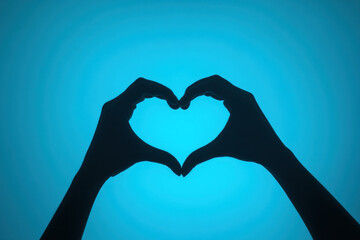 Two hands create a heart shape with fingers against a sunset sky, symbolizing love and connection.