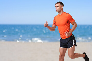 Sporty man running on beach. Space for text