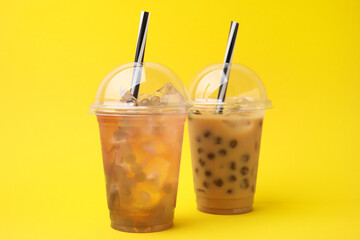 Tasty bubble tea in plastic cups on yellow background
