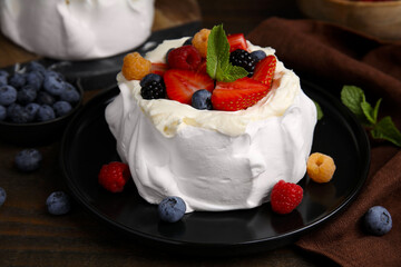 Pavlova cake (meringue dessert) with whipped cream, fresh berries and mint on wooden table, closeup