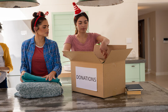 Christmas time, packing donations in box, multiracial female friends at home