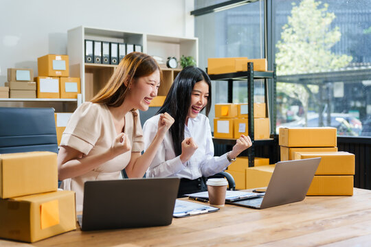 Two young female entrepreneurs work together in warehouse with parcel boxes, wooden tables, and shelves. prepare sales brochures, social media templates, business proposals for small online business. - Powered by Adobe