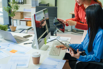 Two young female business consultants work on startup, collaborating on mobile app development...