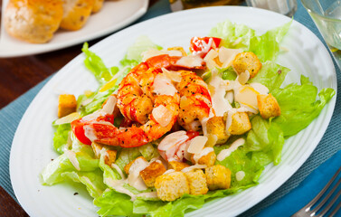 Delicious Caesar salad of romaine lettuce and croutons dressed with delicate sauce topped with shrimps and Parmesan cheese..