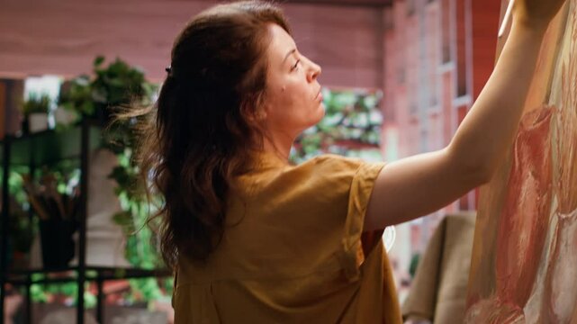 Painter uses her skill and tie dye to create a masterpiece on a canvas in creative workshop, blending colors with a paintbrush. Rustic artwork to life with a special painting technique. Camera A.